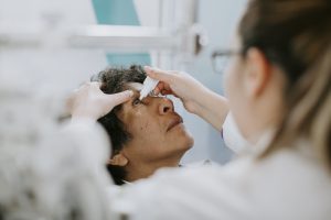 Especialista oftalmólogo aplicando gotas a paciente por ojo seco